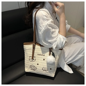 Détail d'un sac cabas en paille tissée avec broderie chat et bandoulière en cuir