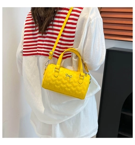 Détail du sac Boston en cuir jaune matelassé cœur avec nœud argenté et bandoulière réglable