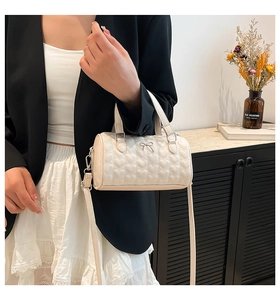 Détail du sac baril crème avec broderie cœur et nœud métallique élégant