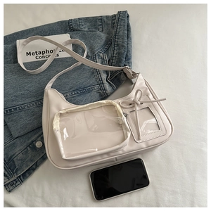 Detail einer beigen Ita-Bag mit transparentem PVC-Fach und dekorativer Schleife