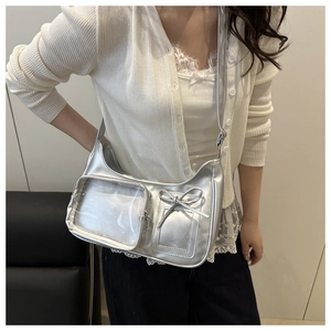 Close-up of silver hobo bag featuring a transparent front pocket and leather bow detail