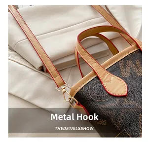 Close-up of golden hardware hook and red-edged leather detail on monogram tote bag