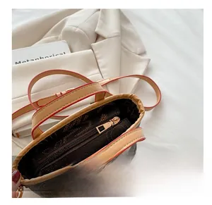 Detail view of the smooth gold-tone metal zipper and brown monogram lining on the tote bag