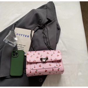 Détail du sac bandoulière en cuir rose avec imprimés cerises et bandoulière en chaîne