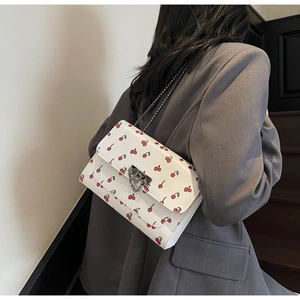 Vue détaillée du sac à bandoulière en cuir PU blanc avec imprimés cerises et chaîne en métal