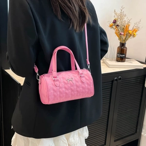 Sac seau rose matelassé avec cœurs et nœud argenté porté par un mannequin chic
