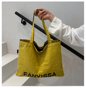 Detail of vibrant yellow canvas tote bag with bold black FANYVISSA logo branding