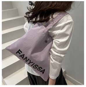 Detail of purple canvas tote bag with FANYISSA letter print on white background