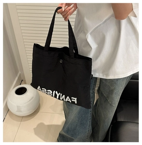 Close-up of black canvas tote bag with white FANYISSA lettering and shoulder strap