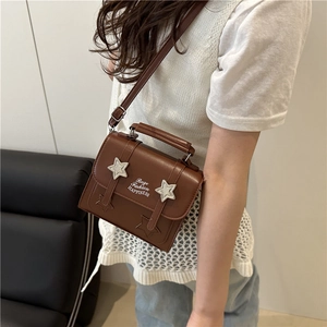 Brown leather mini crossbody bag with silver star accents shown on a model in a side view