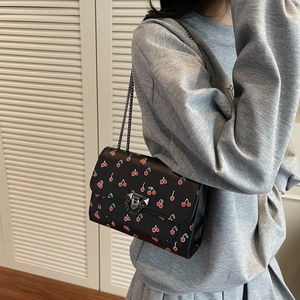 Sac bandoulière tendance avec imprimé cerise et chaîne argentée porté par modèle