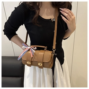 Détail du sac cylindrique marron tressé avec fermoir doré et ruban à carreaux chic
