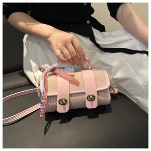 Détail du sac tonneau rose tissé avec fermoir doré et décoration de ruban en dentelle