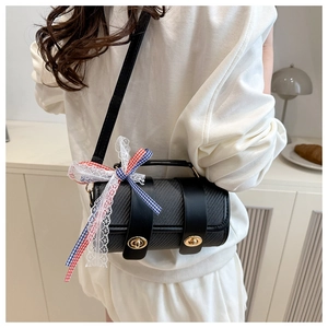Détail du sac cylindrique noir avec nœud à carreaux et dentelle sur un canapé