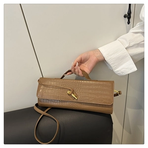 Dettaglio della borsa marrone con motivo coccodrillo, chiusura dorata e tracolla sottile