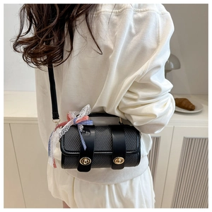 Gros plan sur un sac cylindre noir avec texture en carbone et accessoire nœud