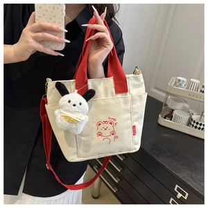 Detail of canvas tote bag featuring contrast red straps and a cute cartoon bear print