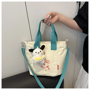Détail du cabas en toile beige avec anses bleues et breloque chiot en peluche