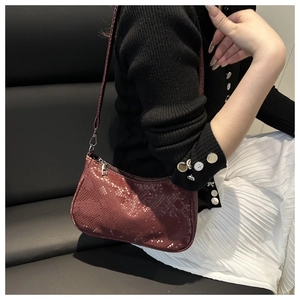 Detail of burgundy crocodile pattern faux leather shoulder bag with silver zipper closure