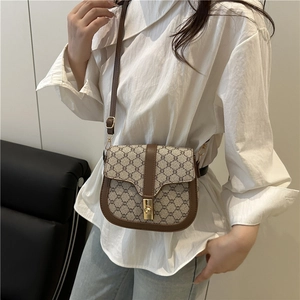 Vintage brown leather saddle bag with geometric patterns worn over a white shirt