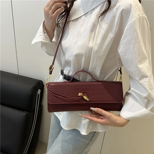 Borsa baguette bordeaux minimalista con trama coccodrillo e fibbia a nodo dorato indossata