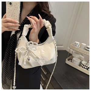 Detail der cremeweißen Handtasche mit Perlenspitze-Schleife und gerafftem Griff