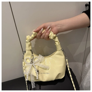 Detail der hellgelben Handtasche mit Spitzenschleife und großer Perlenverzierung