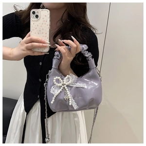 Detail der fliederfarbenen Lackleder-Handtasche mit Perlschleife, Spitze und Raffgriff