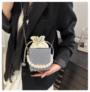 Detail of mini box bag featuring pearl handle, metal chain, and geometric jacquard fabric