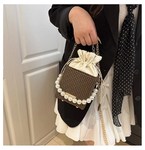 Detail of pearl handle and drawstring pouch inside a monogrammed crossbody handbag
