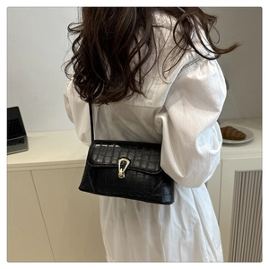Detail of black crocodile texture bag with gold horseshoe buckle on white shirt dress