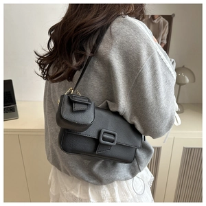 Detailed view of black litchi grain leather baguette bag with a mini pouch attachment