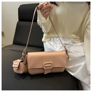Detail of pink lychee grain leather baguette bag with mini coin purse charm and gold buckle