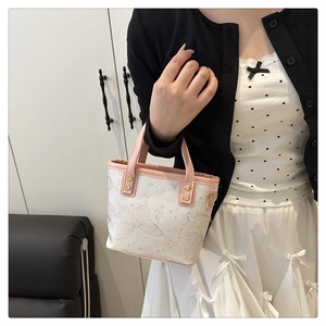 Détail du sac seau imprimé papillon avec poignées en cuir rose et clous dorés