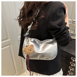 Silver metallic crescent shoulder bag featuring a knotted strap and cute plush bear charm
