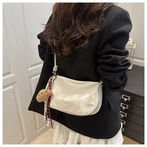 Creamy white patent leather pillow bag with plush bear charm and plaid scarf detail