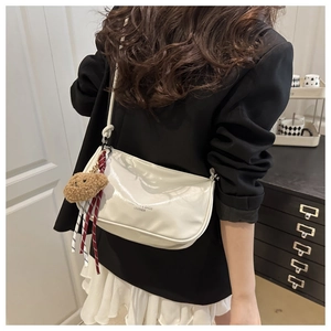 Détail du sac croissant blanc en cuir brillant avec pendentif ours et ruban