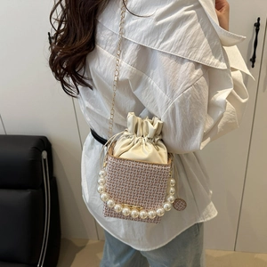 Minimalist cream woven bucket bag with pearl handle, chain strap and repeat logo pattern