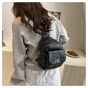 Close-up of quilted black leather backpack featuring metal chain straps and twist-lock pocket