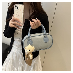 Detail of light blue lychee pattern faux leather handbag with cute plush bear charm