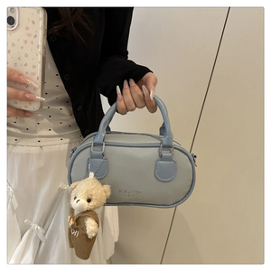Close-up of light blue mini Boston bag in pebble leather with a cute plush bear charm