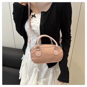 Detailed view of pink barrel bag with lychee pattern leather and silver hardware on a model