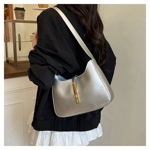 Borsa a spalla in pelle argento con fibbia dorata indossata da modella in un caffè