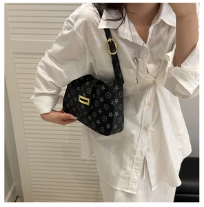 Detail of vintage star pattern on black shoulder bag with gold clasp and adjustable strap