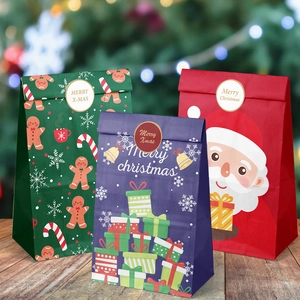 Trois sacs cadeaux de Noël en papier assortis avec motifs Père Noël et pain d'épices sur bois