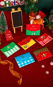 Close-up of Christmas folding cards with reindeer and snowman designs on red cloth