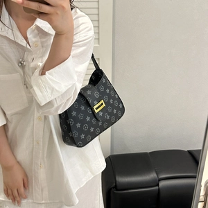 Classic black star pattern underarm bag with gold metal buckle shown on a model