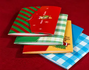Detail of colorful Christmas cards with reindeer and tree designs on red fabric background