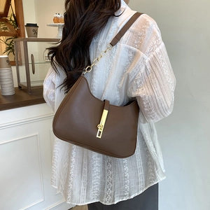 Sac hobo marron avec fermoir doré et bandoulière chaîne porté par un mannequin