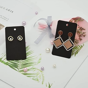 Set of gold geometric pearl stud and dangling diamond earrings on black display card